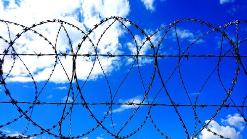 Low angle view of barbed wire against blue sky