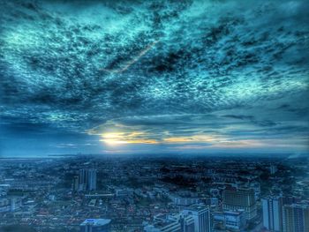 Aerial view of cityscape against cloudy sky