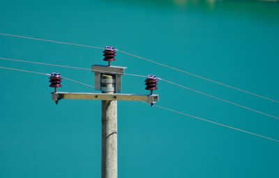 Low angle view of power pole against blue sky