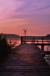 Silhouette pier over lake against sky during sunset