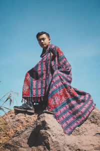 Low angle view of man sitting on land against clear sky