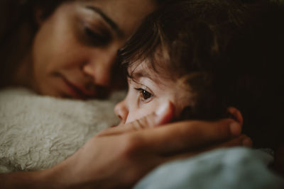 Woman touching daughter on bed