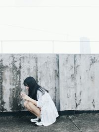 Full length of woman crouching by railing