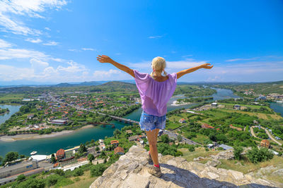 Rear view of woman standing on mountain against sky