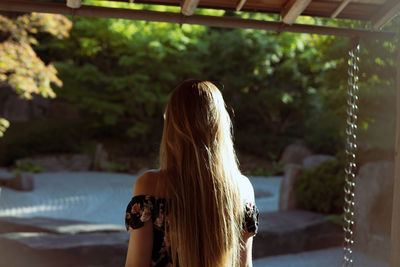 Rear view of woman standing against trees