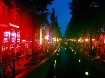 Panoramic shot of illuminated canal in city at night