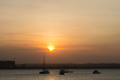 Silhouette of boats sailing in sea during sunset