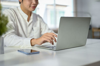 Midsection of businesswoman using laptop at office