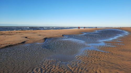 Scenic view of beach against clear blue sky