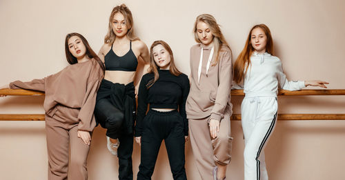 Portrait of a group of women standing against the wall