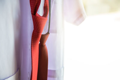 Close-up of necktie and clothing hanging against wall