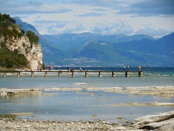 People on pier against mountains 