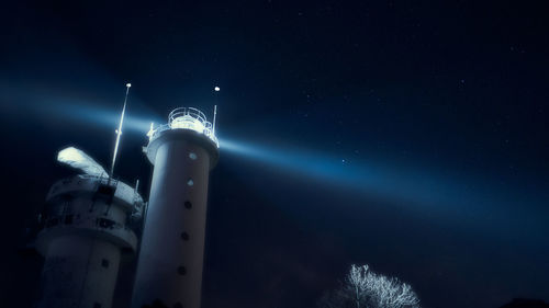 Low angle view of illuminated lighthouse against sky at night