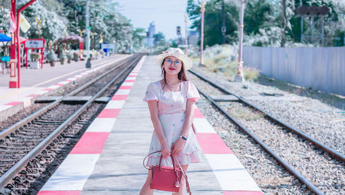 Portrait of smiling woman standing on railroad station platform