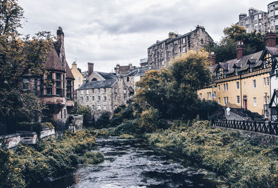 Buildings by river against sky in city