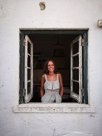 Smiling young woman looking through window