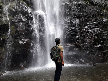 Rear view of man standing against waterfall