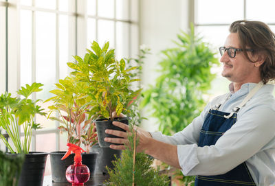 Side view of man holding potted plant
