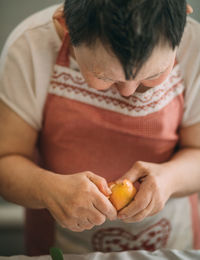 Lifestyle, education. elderly woman with down syndrome is studying in kitchen peel tangerine 