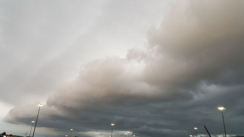 Low angle view of illuminated street light against cloudy sky