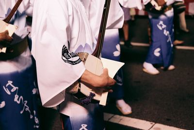 Midsection of artists playing shamisen on street during awa odori