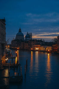 Illuminated buildings in city against sky at dusk
