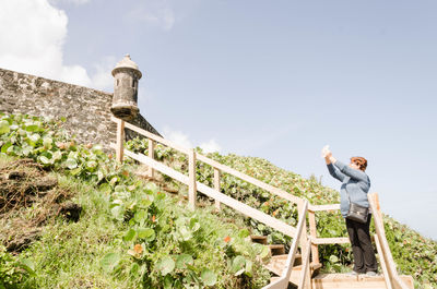 Woman photographing old ruin against sky