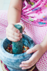 Cropped image of girl using mortar and pestle