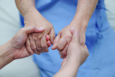 Cropped image of doctor holding hands with female patient in hospital