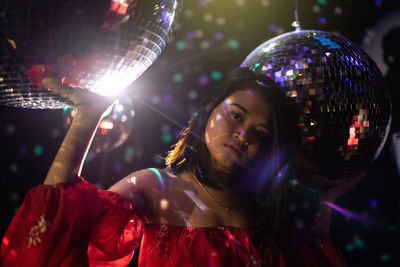 Portrait of young woman standing amid disco balls at nightclub