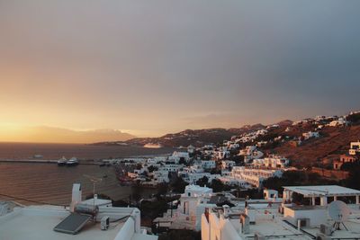 Cityscape by sea against sky during sunset