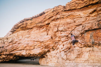 Low angle view of person on cliff against sky