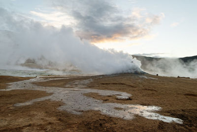 Smoke emitting from volcanic landscape against sky