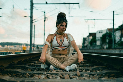 Young woman sitting on railroad track
