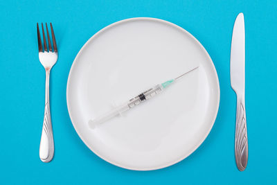 High angle view of empty plate on table against blue background