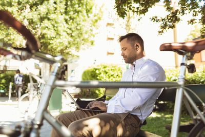 Side view of businessman using laptop while sitting on park bench