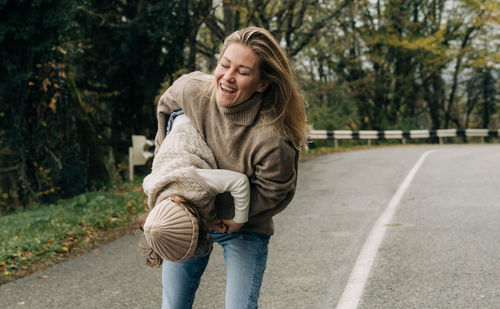 Laughing mother circling her little daughter in her arms on a rural road.