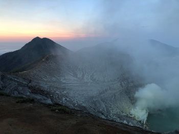 Smoke emitting from volcanic mountain during sunset