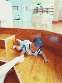 High angle view of boy lying on hardwood floor at home