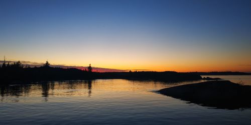 Silhouette bridge over river against sky during sunset