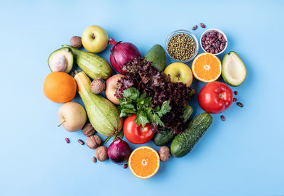 Healthy diet. fresh fruit and vegetables in heart shape top view flat lay on blue background