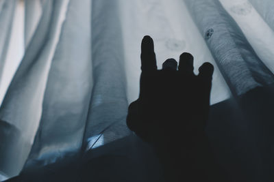 Close-up of silhouette hand on bed