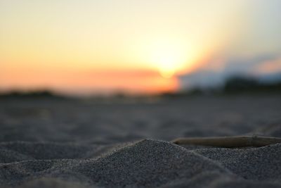 Close-up of sand at beach against sky during sunset