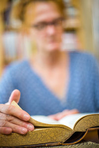Close-up of woman reading book on table in library