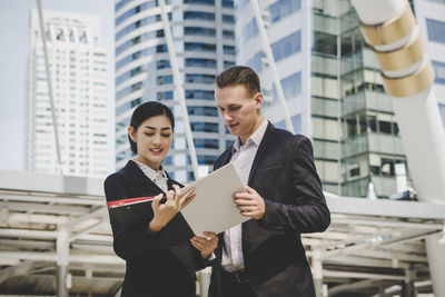 Low angle view of business people discussing while standing against building