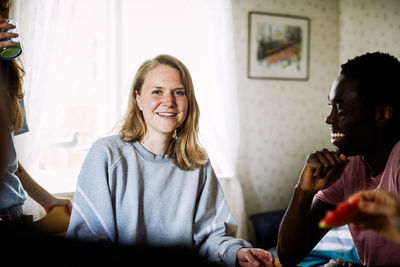 Portrait of smiling young woman enjoying social gathering with friends at home