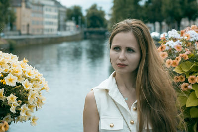 Close-up portrait of young woman with flowers against blurred background