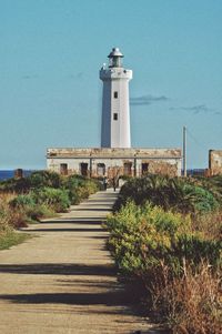 View of lighthouse by building against clear sky