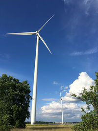 Low angle view of windmills against sky