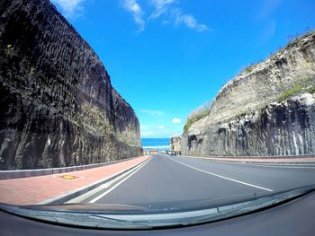 Road amidst mountains seen through car windshield